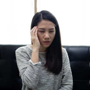 Young woman with headache holding her temple, a typical sign of iron deficiency symptoms