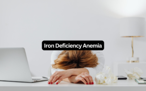 Woman resting her head on her arms at a desk, exhausted from iron deficiency anemia fatigue